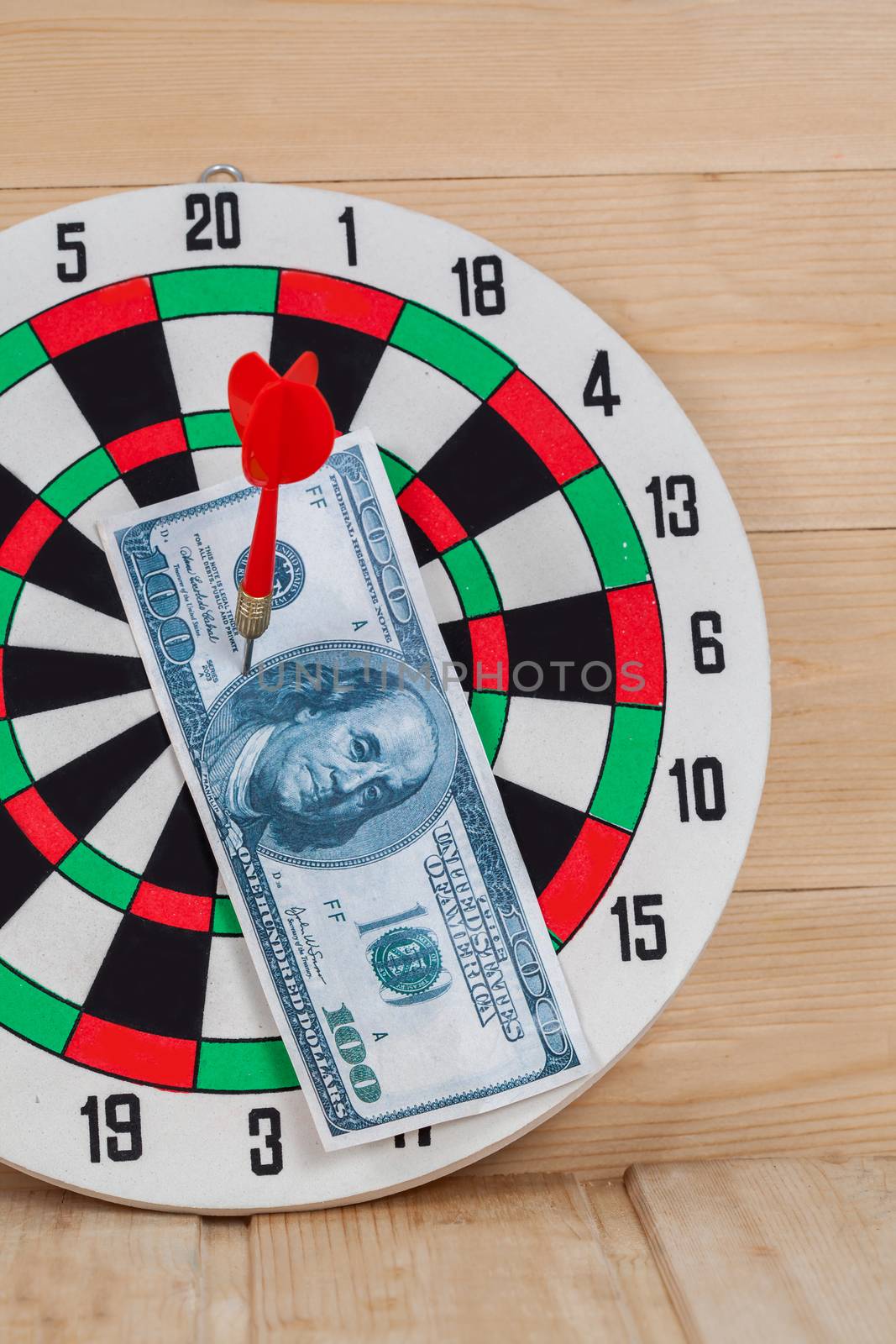 Dart arrow hitting in bullseye on dartboard with money
