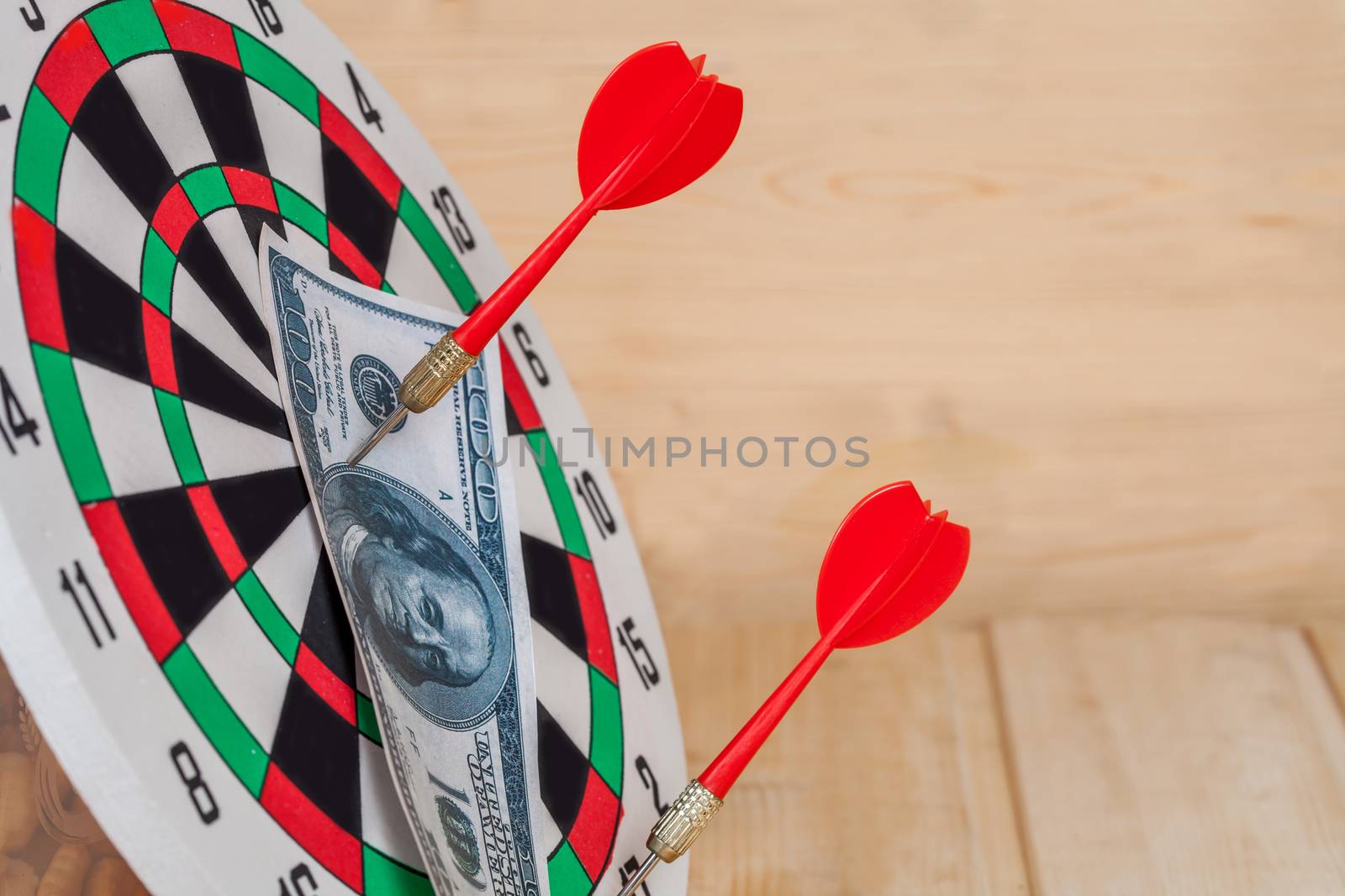 Dart arrow hitting in bullseye on dartboard with money