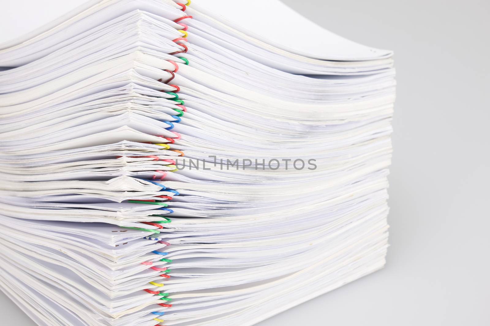 Pile overload paperwork of receipt and report with colorful paperclip on white background.