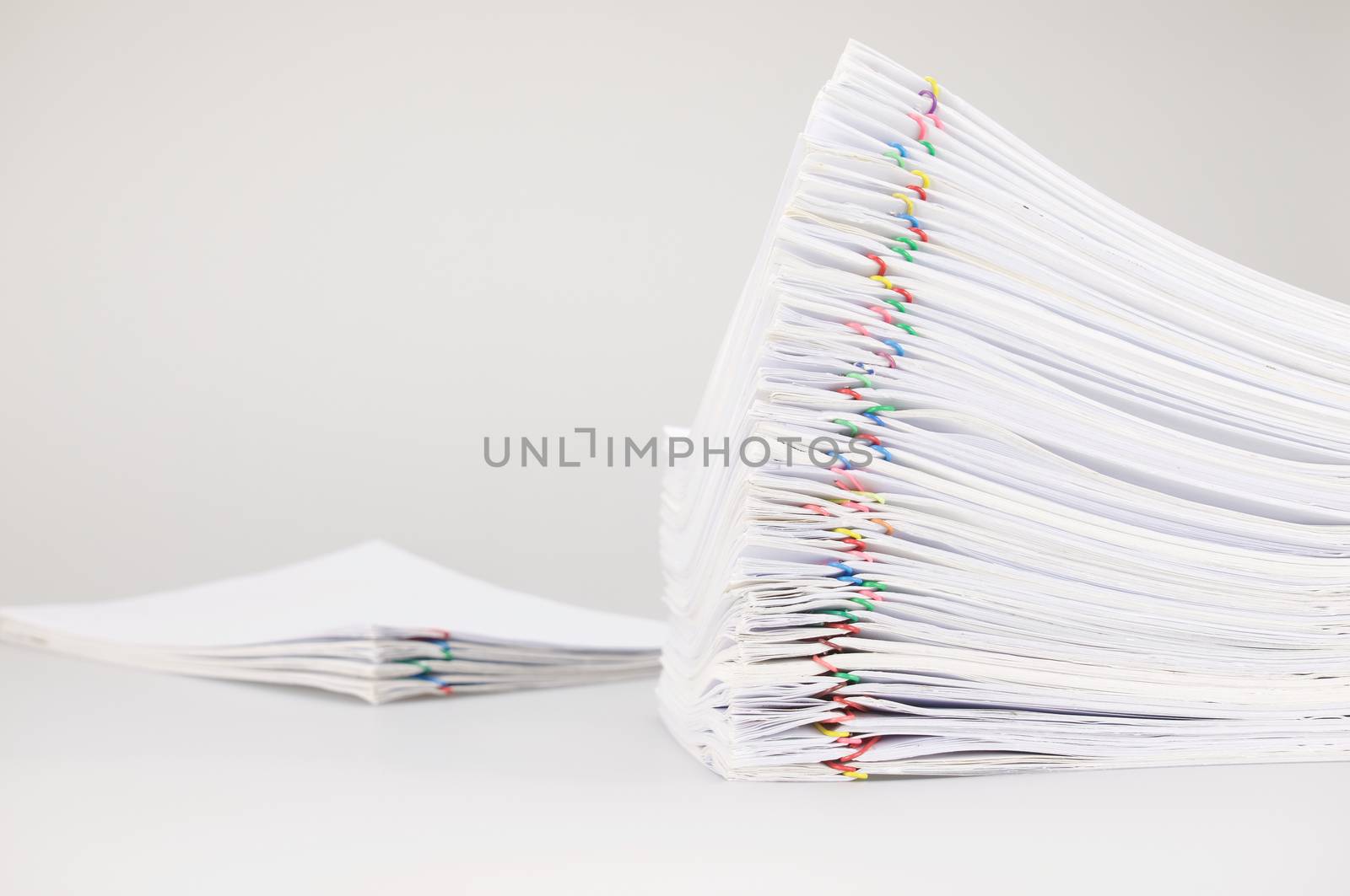 Pile overload paperwork of receipt and report with colorful paperclip with blur pile document place on white background.