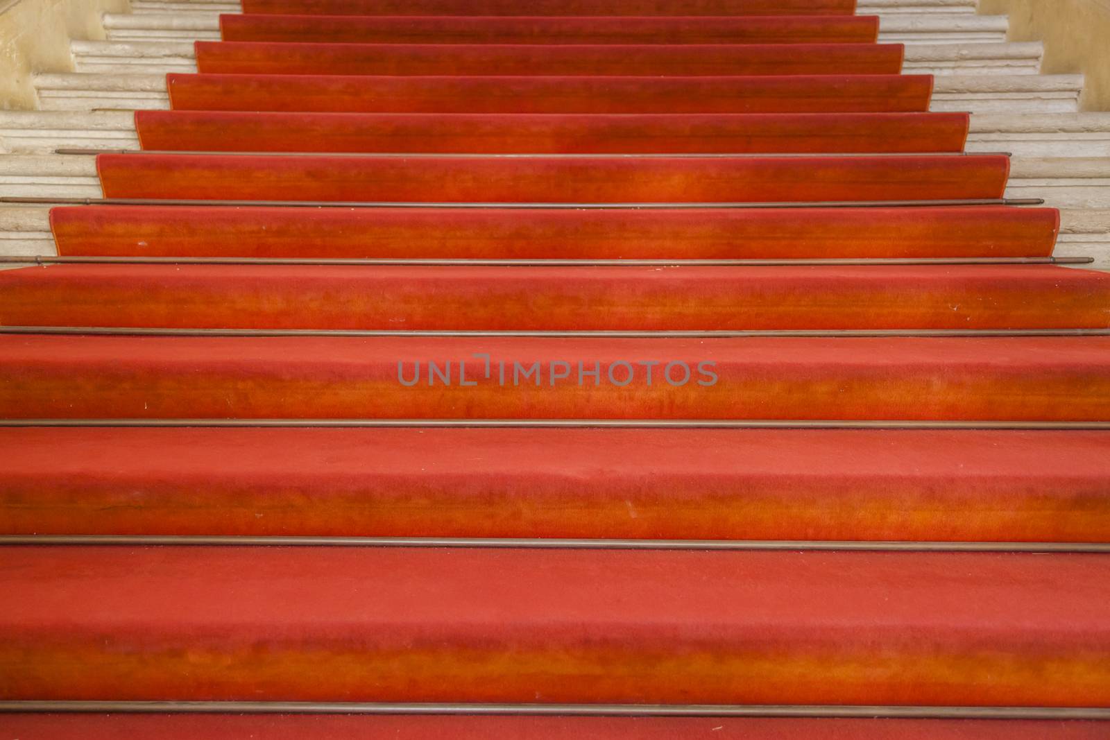Ancient stairs with red carpet in an old building in Italy