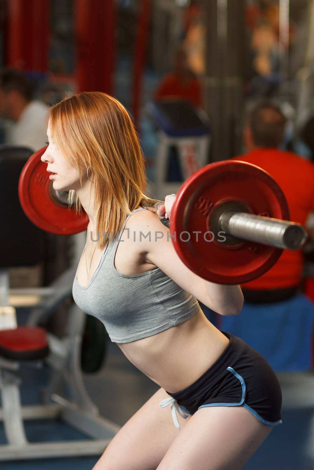 Concept: sport, healthy lifestyle. Young strong girl do squats with a barbell