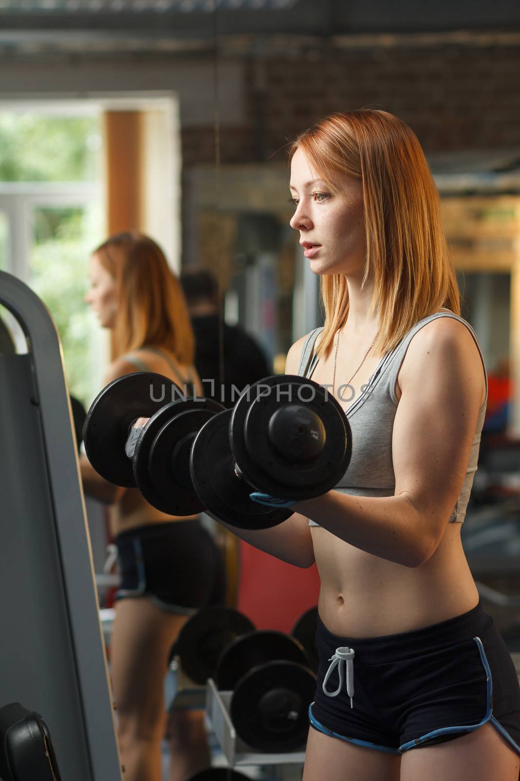 Concept: sport, healthy lifestyle. Young strong girl do exercises with dumbbells