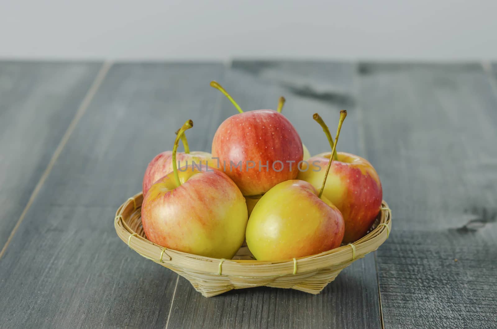 Red and yellow apple  with bamboo basket , organic fresh fruit on white  wooden background