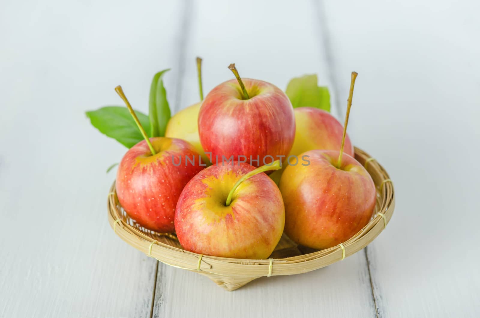 Red and yellow apple  with bamboo basket , organic fresh fruit on white  wooden background