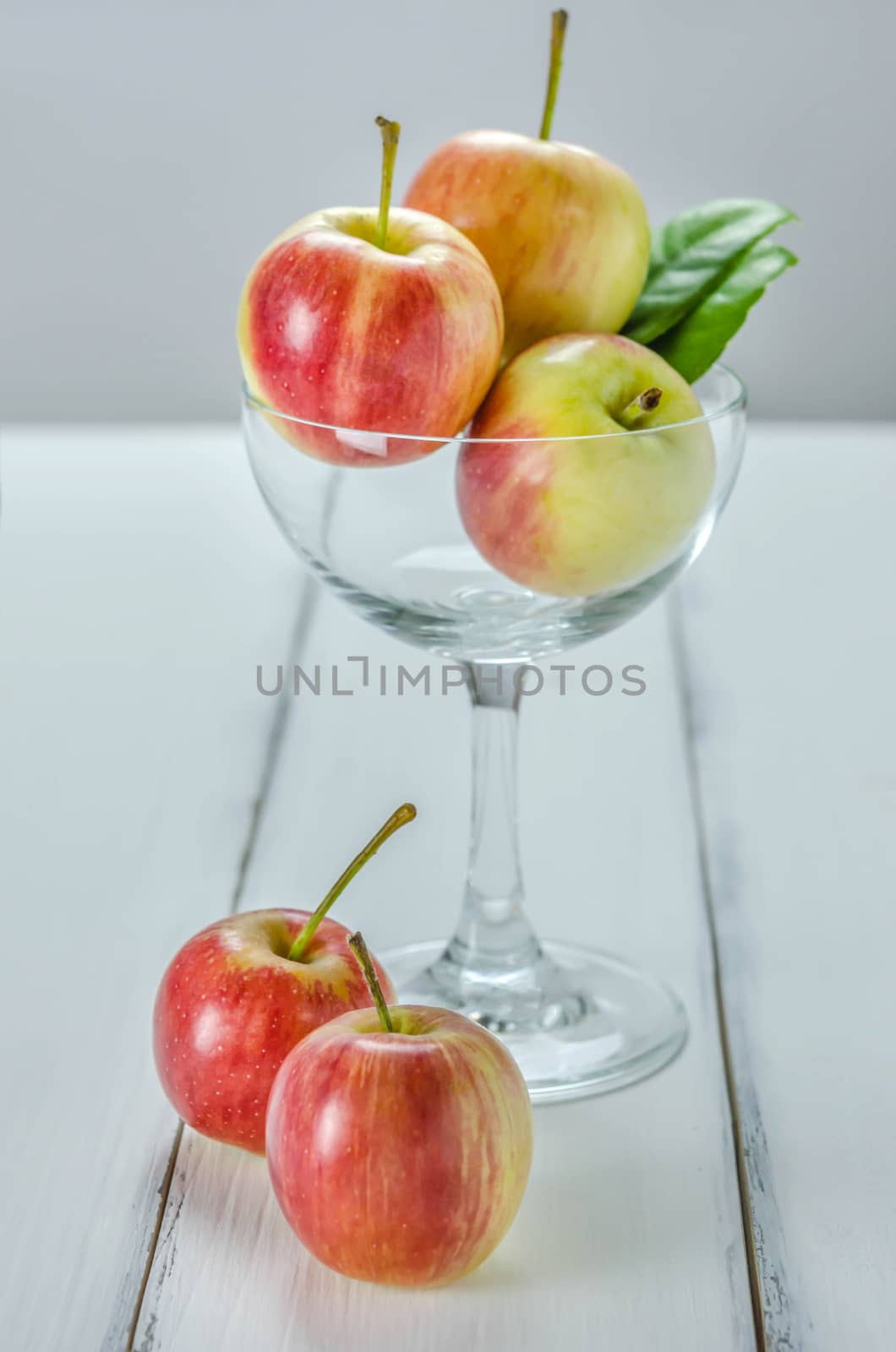 fresh red and yellow apple with glass on wooden background