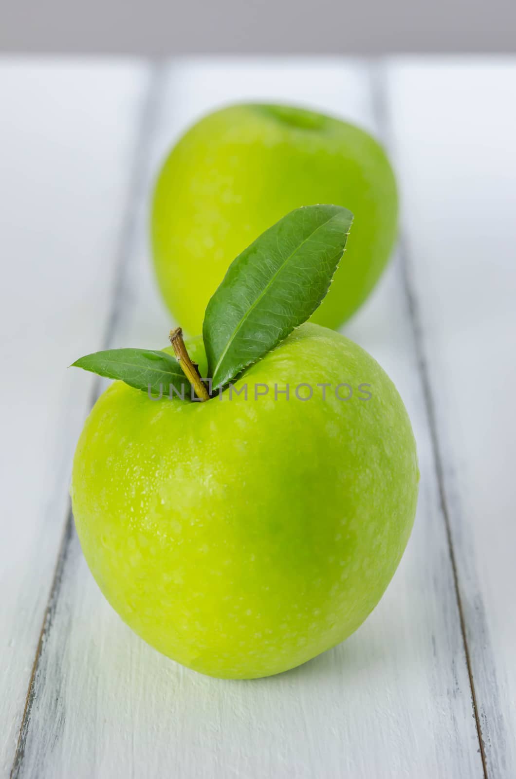 Ripe green apple with leaf  on a wooden background
