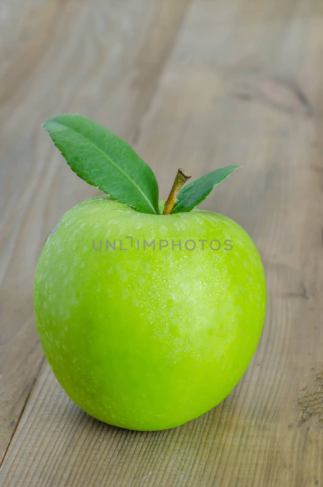 Ripe green apple with leaf  on a wooden background