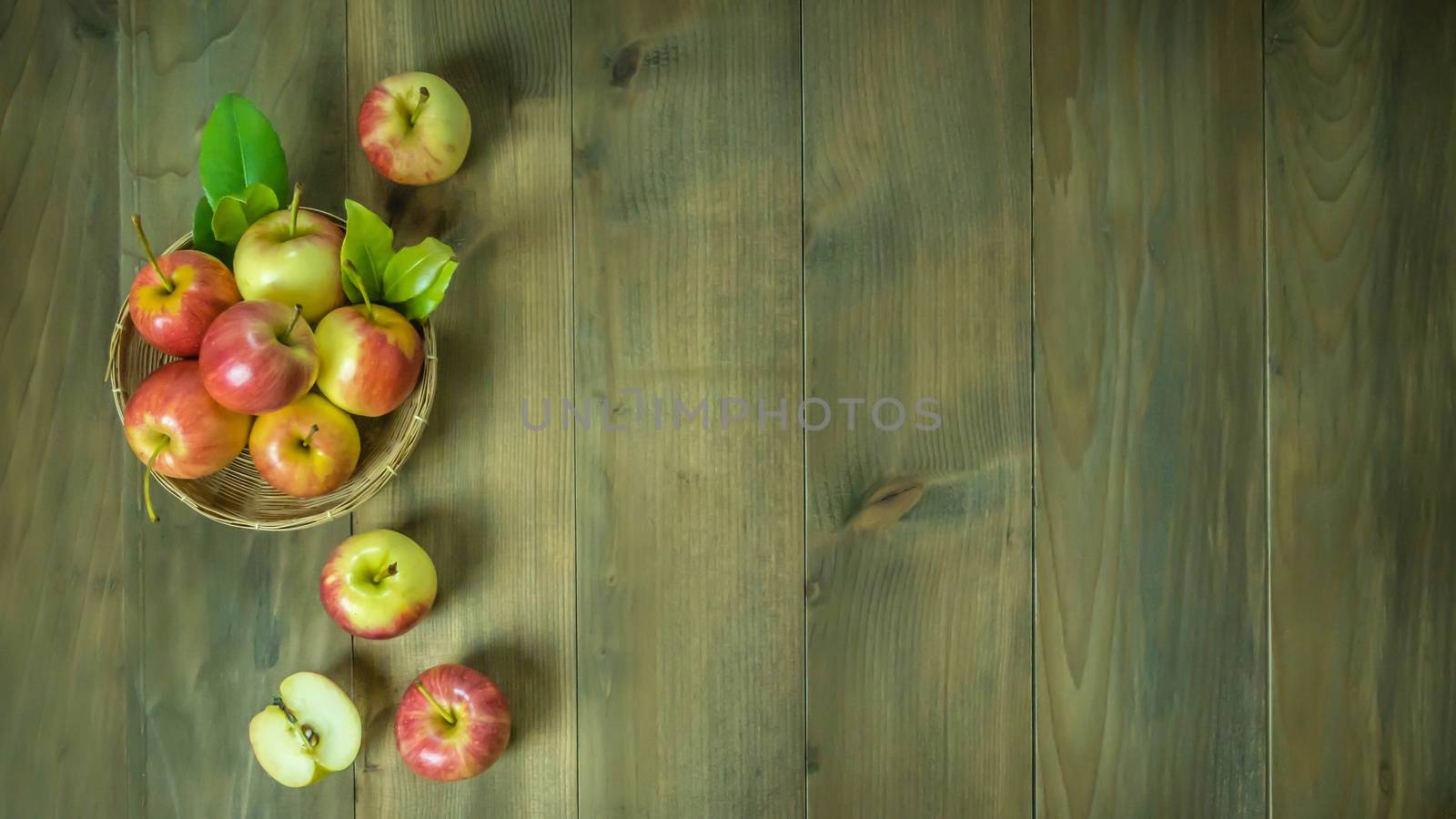 Top view red and yellow apple with leaves and  bamboo basket on wooden background with free space for text
