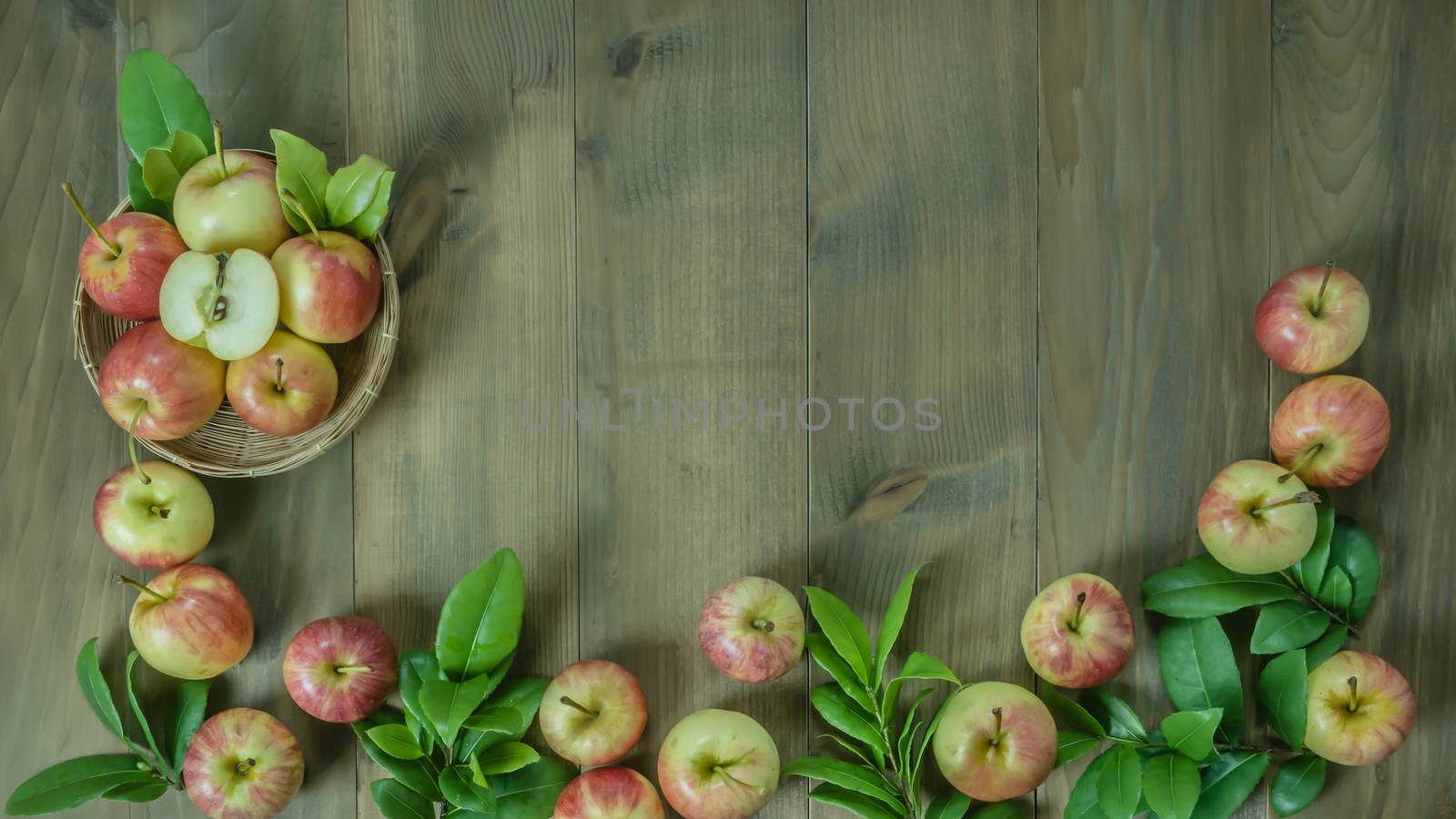Top view red and yellow apple with leaves and  bamboo basket on wooden background with free space for text