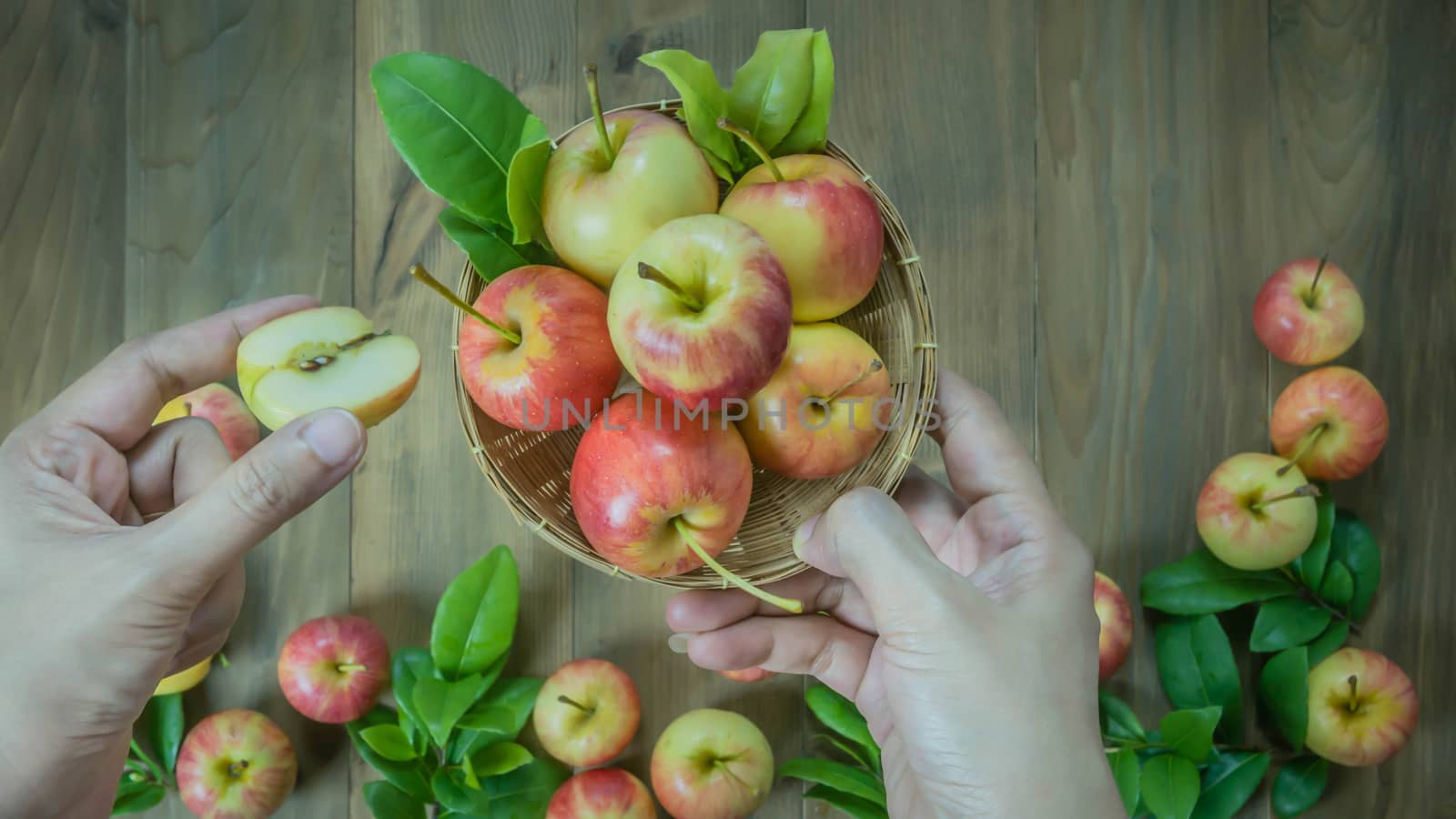 human hand holding red and yellow apple  on wooden background , Top view