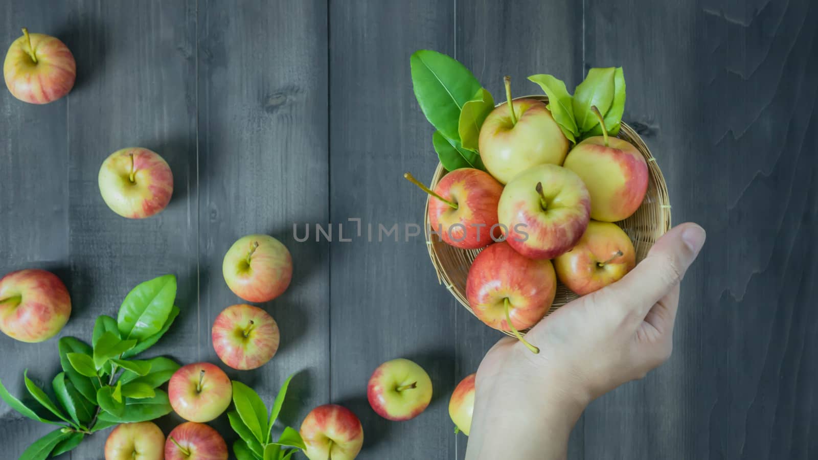 human hand holding red and yellow apple  on wooden background , Top view