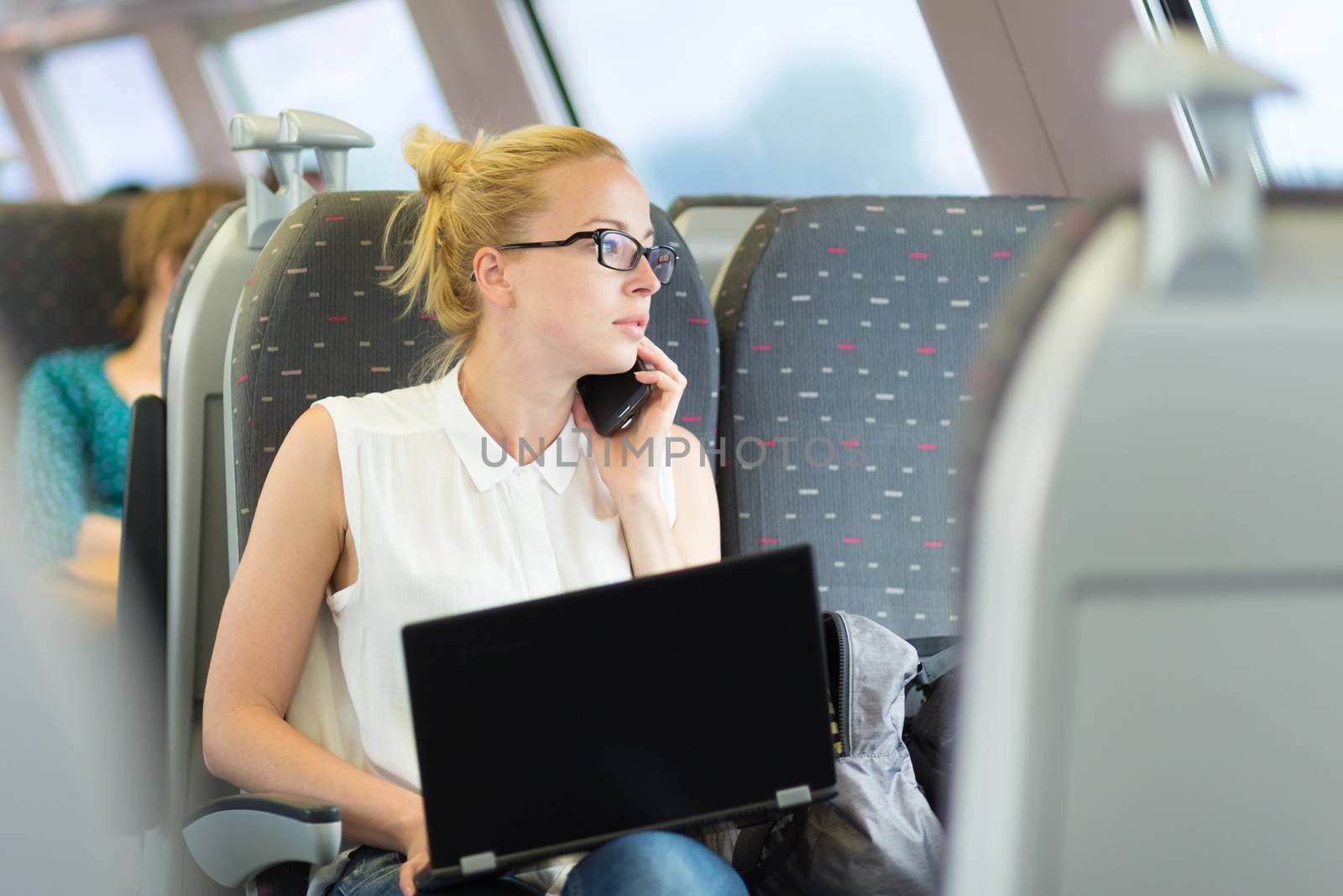 Business woman working while travelling by train. by kasto