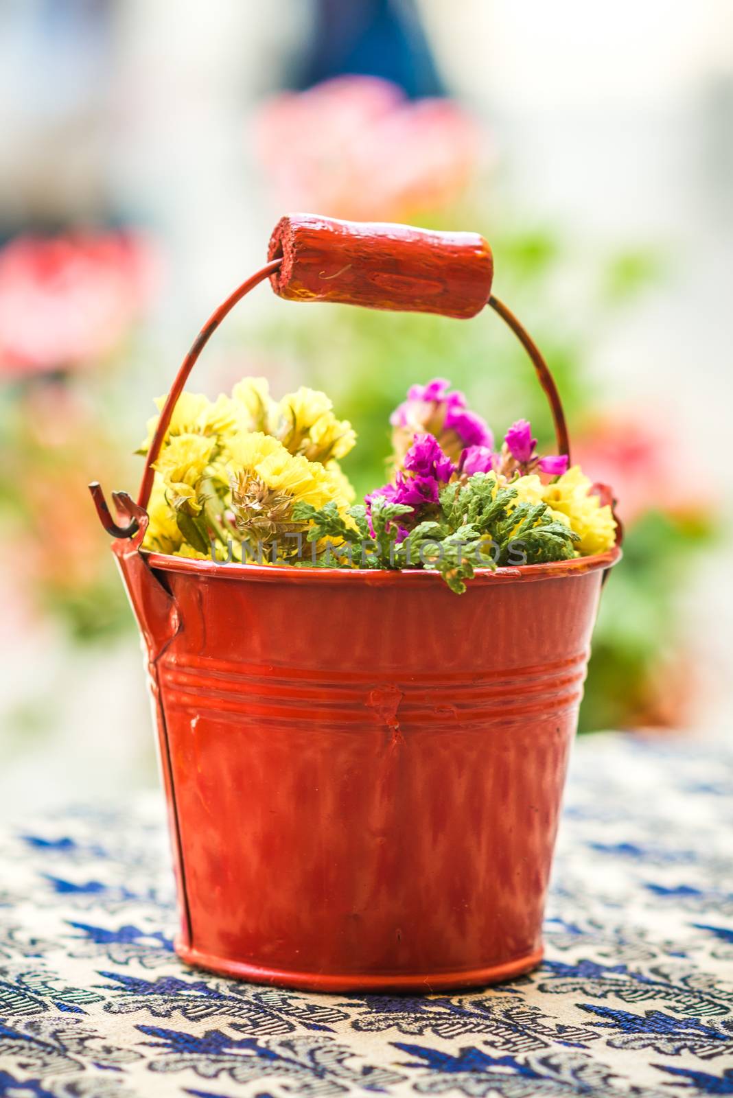 old red metal bucket decorated with yellow flowers on the table
