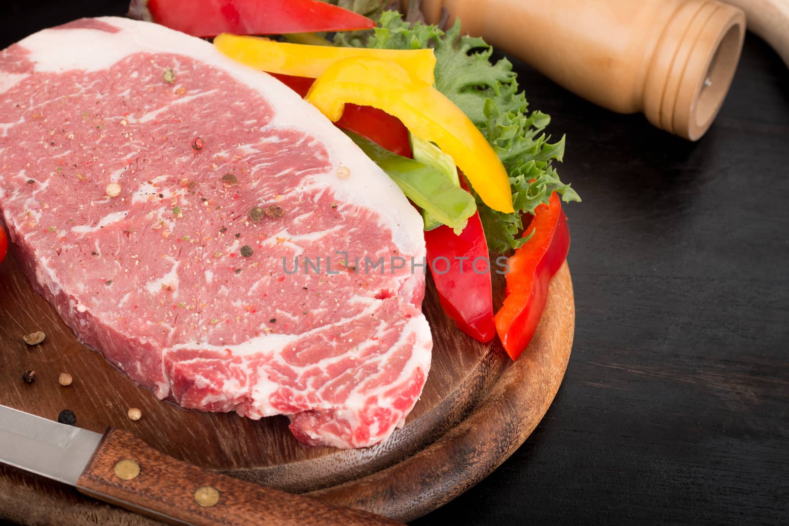 raw pork steak with vegetables on wooden background