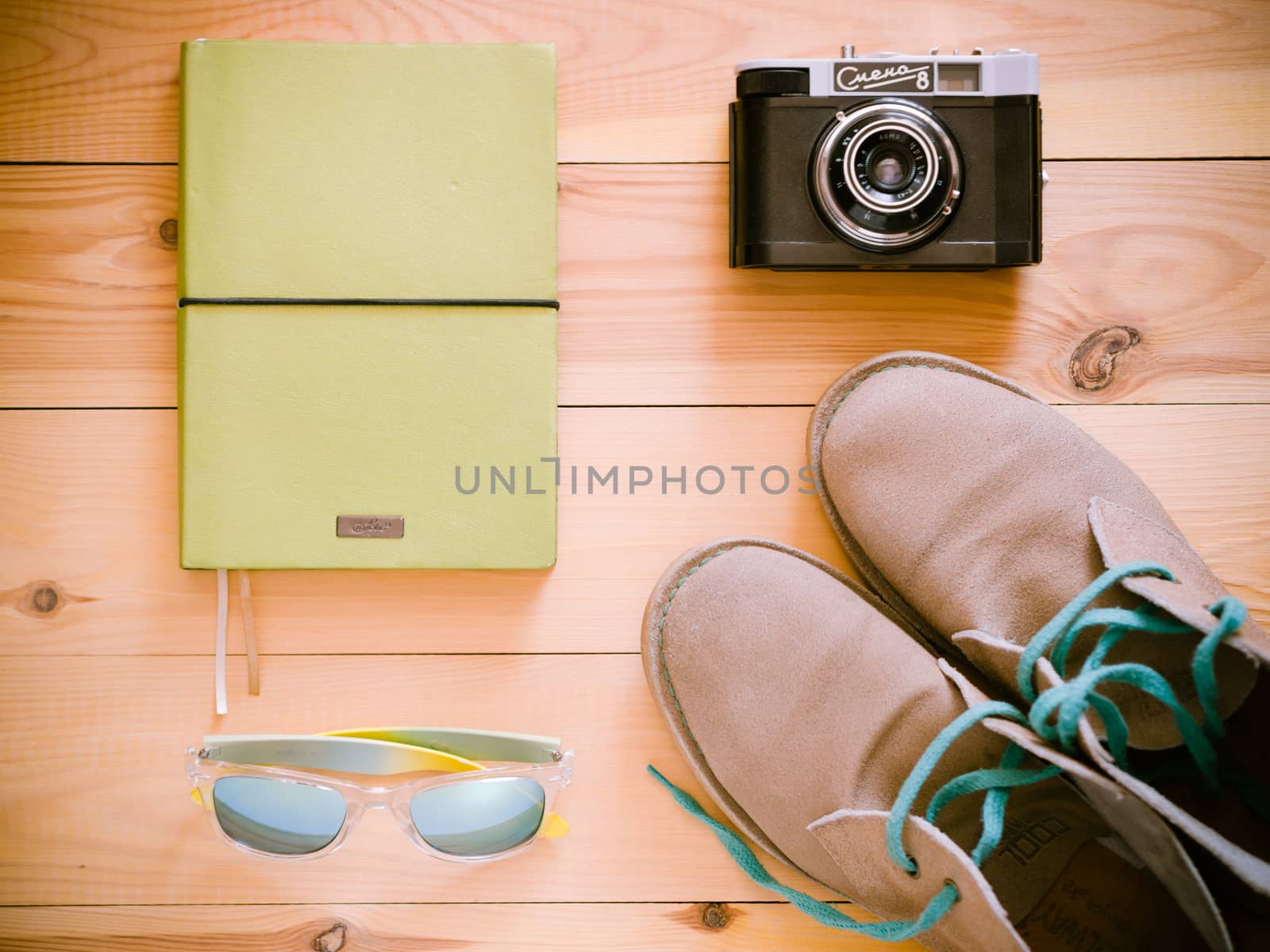 Set of travel and resort stuff. Old 35 mm camera, note book, sunglasses and desert boots on wooden table. Top view, flat lay