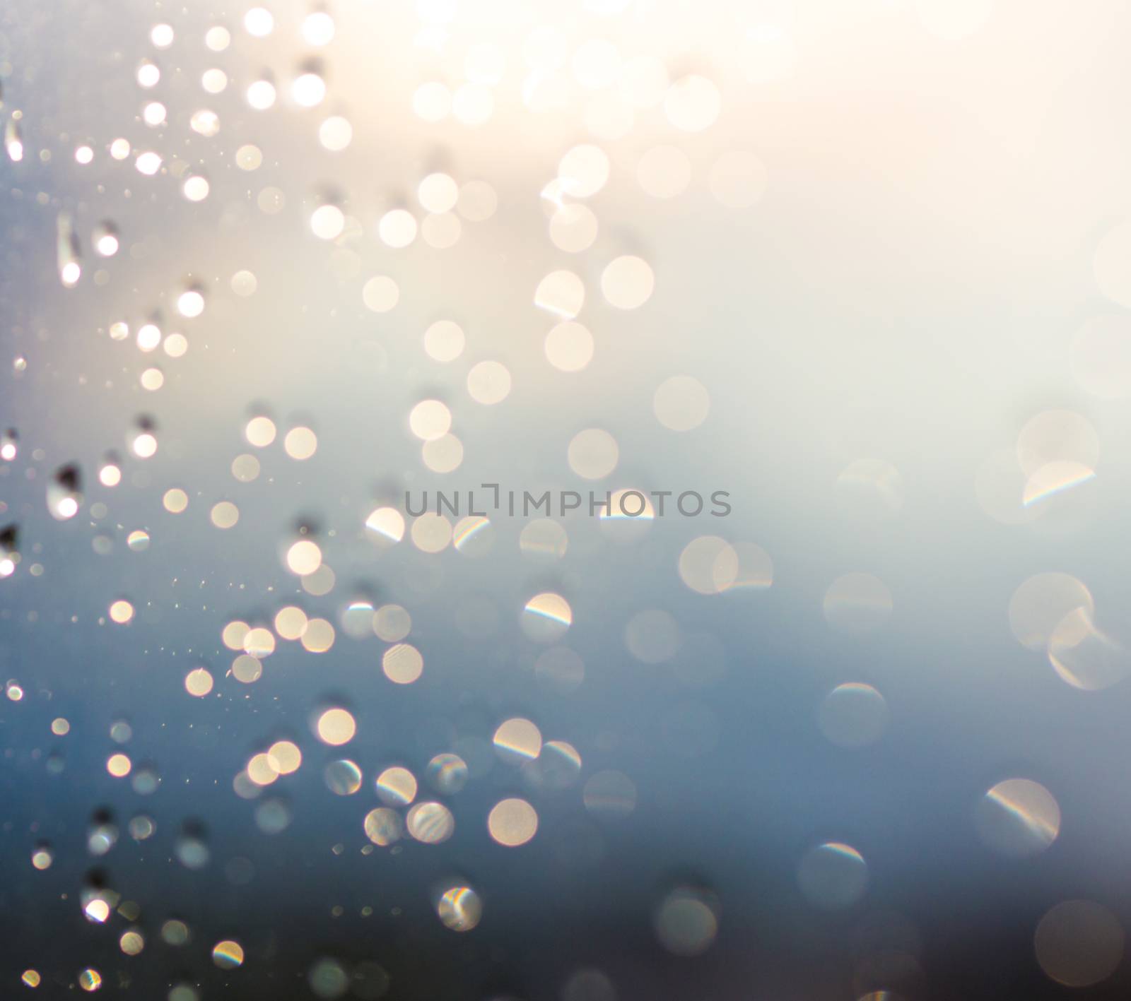 Blurred water drops of rain on blue glass with bokhe as background. Blurred rain drops on window