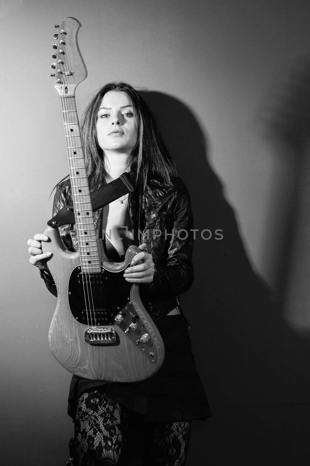 Serious woman standing with electric guitar by sumners