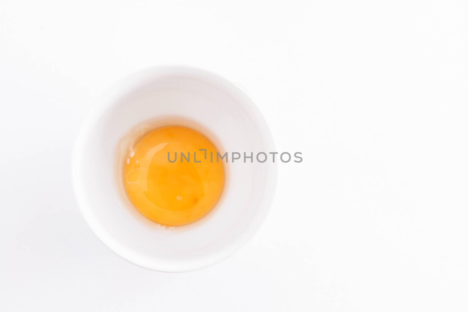 raw egg yolk in a bowl on a white background.