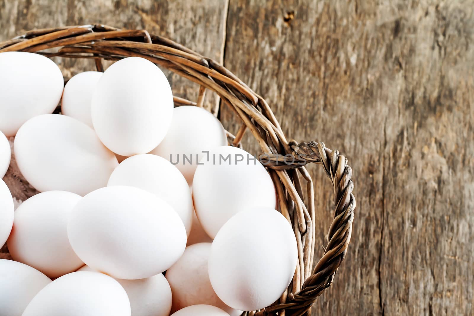 Chicken eggs in the basket on wooden background.