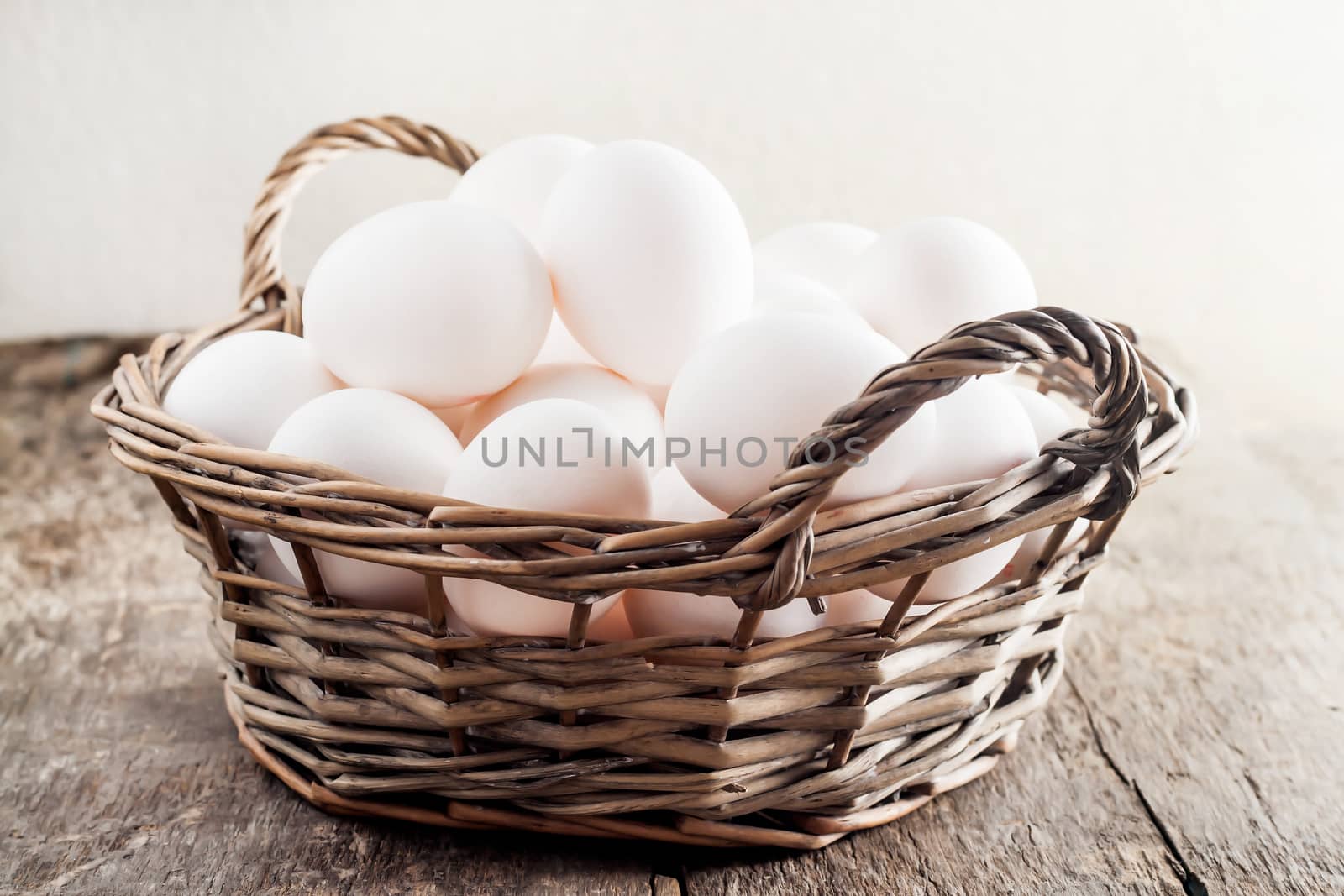 Chicken eggs in the basket on wooden background.