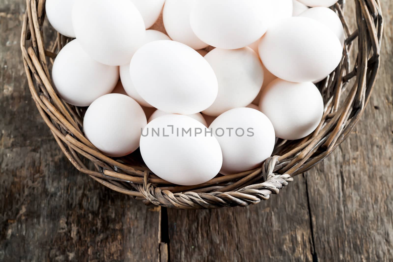 Chicken eggs in the basket on wooden background.