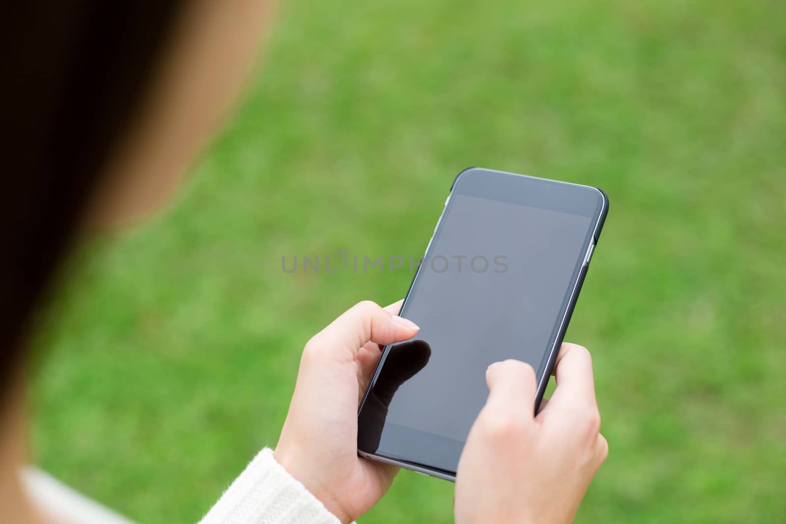 Woman use of cellphone over green grass by leungchopan