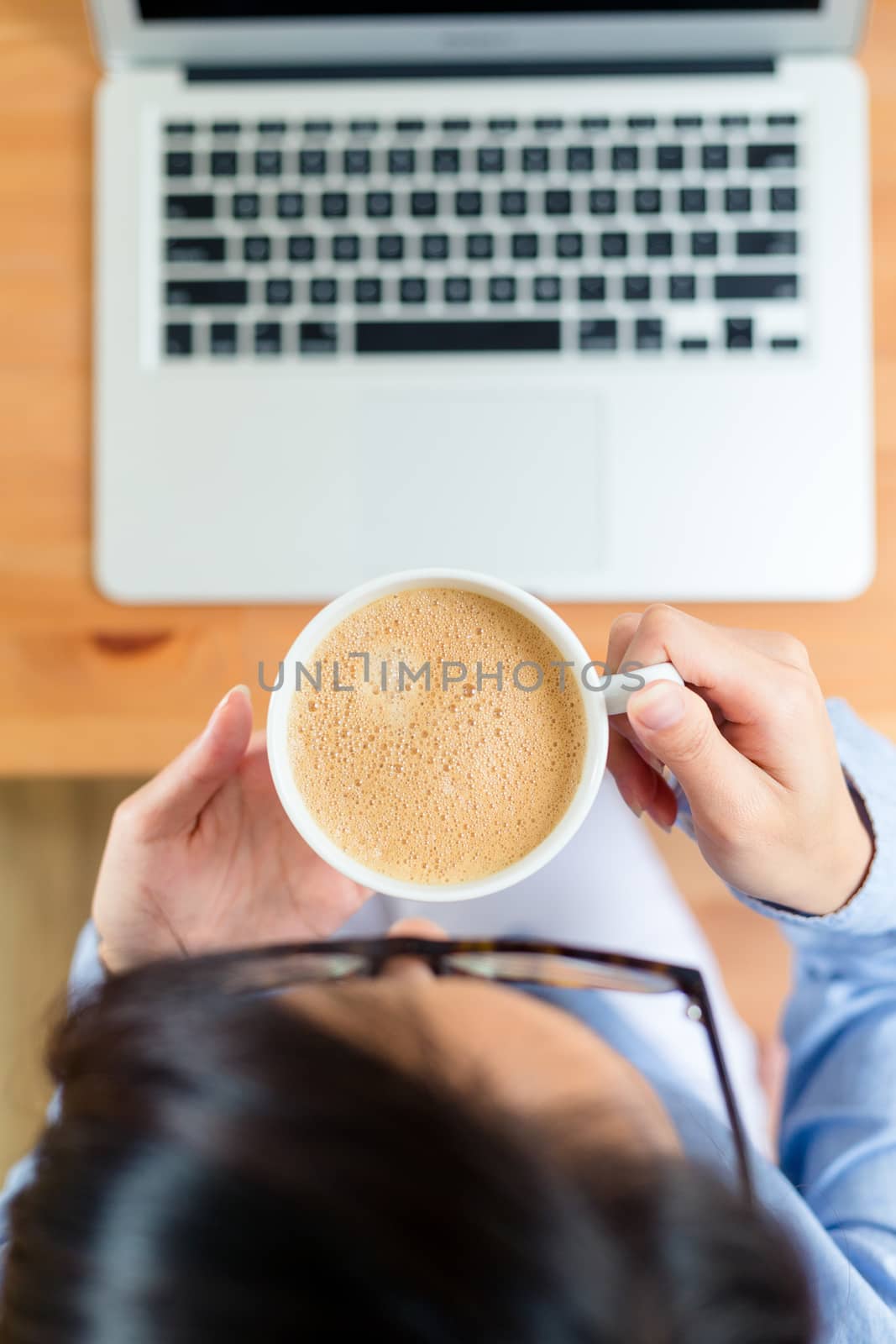 Top view of woman drink of coffee with her laptop computer by leungchopan