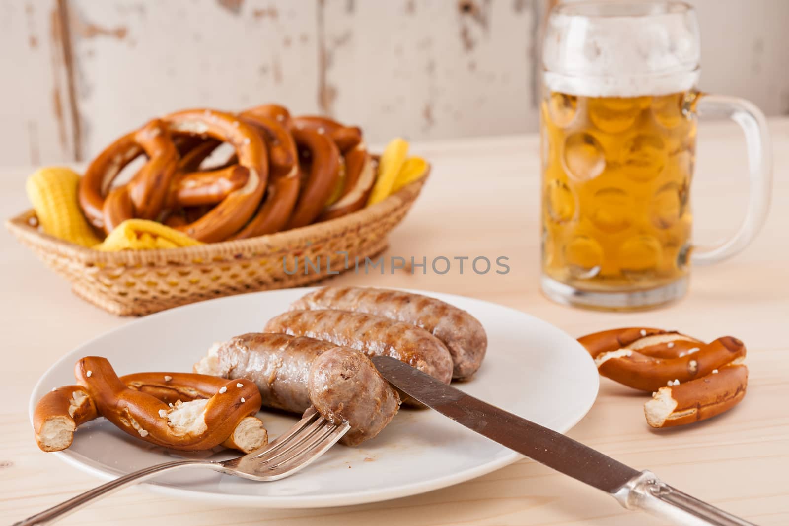 Bavarian cooked sausage and pretzel on a breadbasket and beer on background
