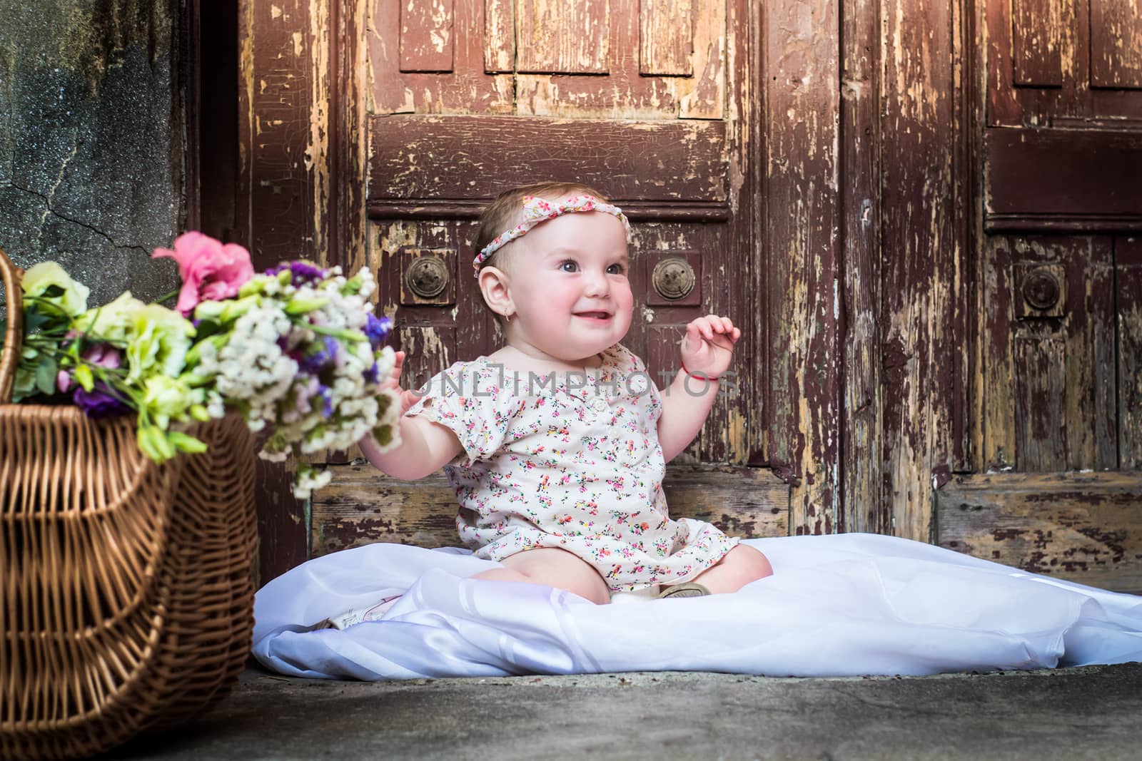 Portrait of beautiful smiling baby girl on the background of the vintage old door. Close-up