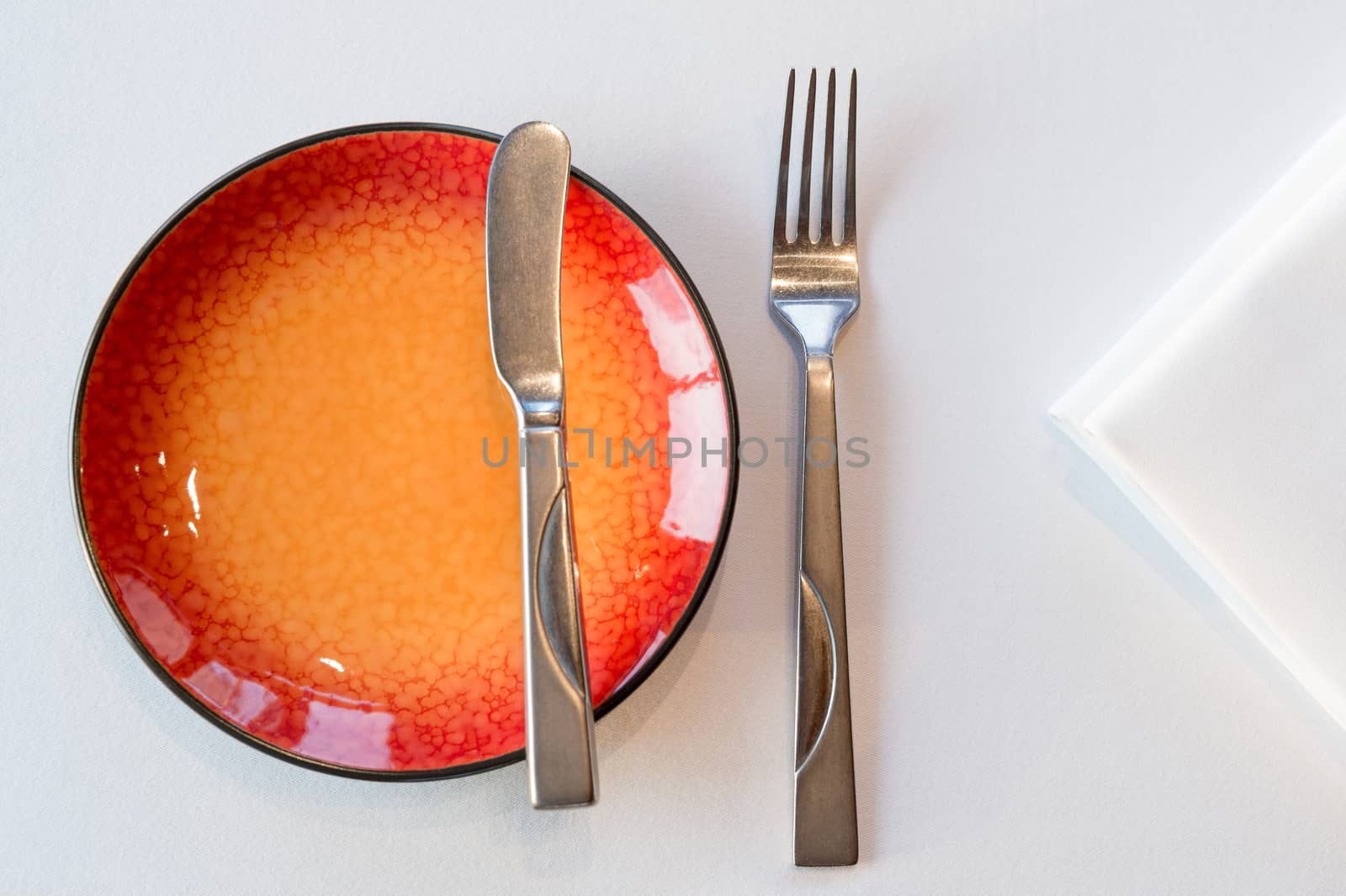 Starter meal setup with red hot plate and white napkin decoration. Selective focus.