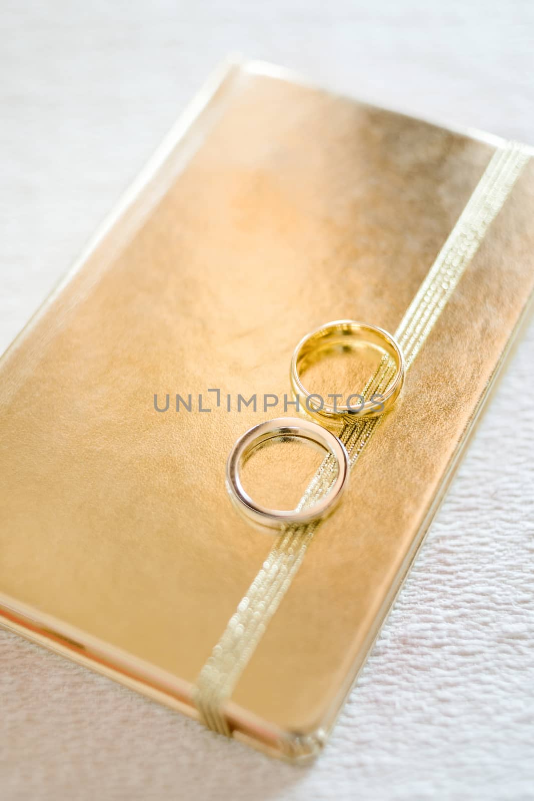 Wedding rings on golden book of memory, selective focus