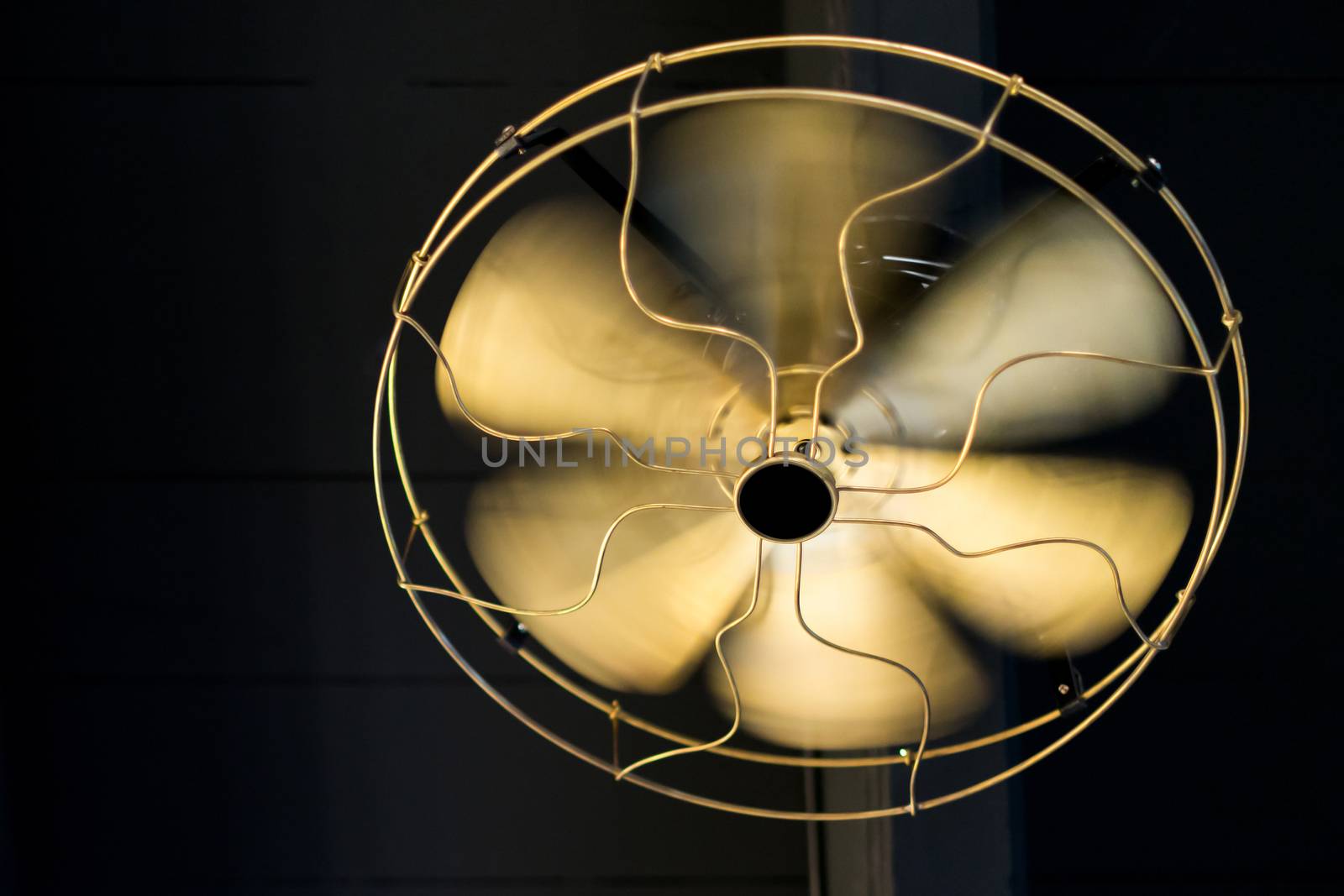 Close up brass ceiling fan on black wooden background.