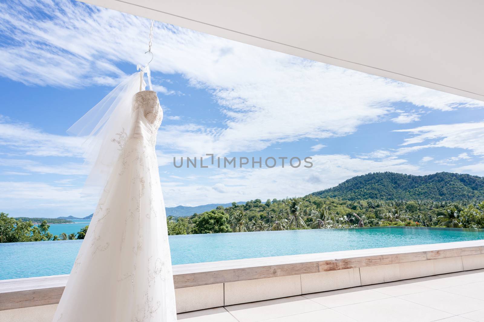 White Wedding dress hanging on a shoulders, beautiful blue sky background.