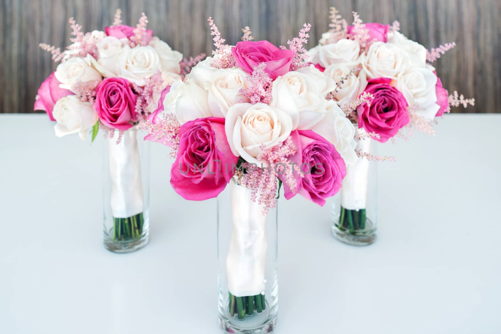 Mixed white & pink roses bouquets on white table, wooden background. Selective focus.