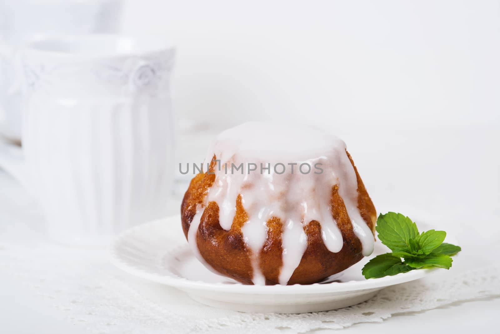 Rum baba cake on plate on light background