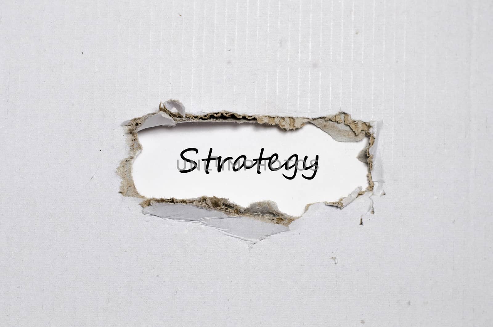 The word strategy appearing behind torn paper
