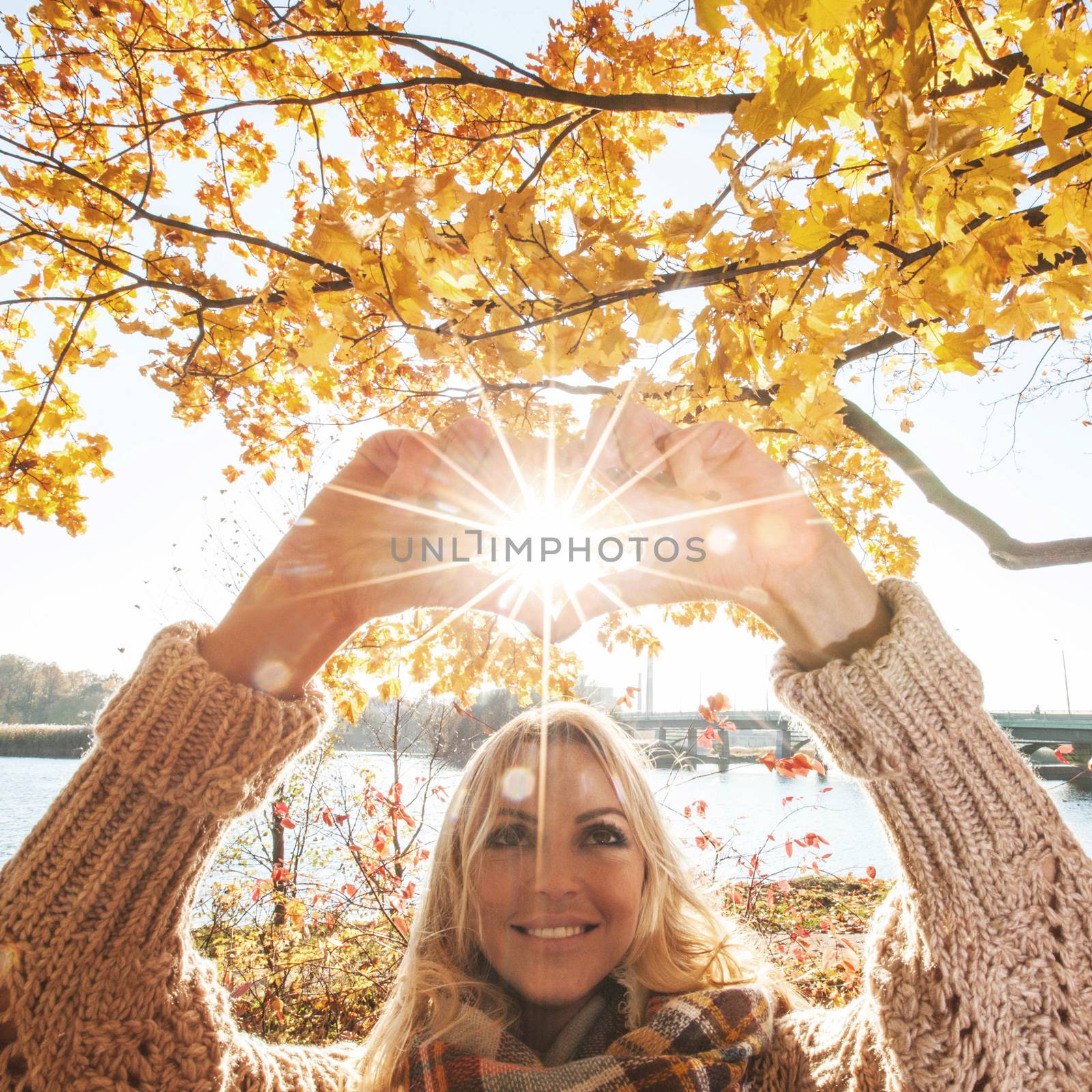 Happy woman playing with sun in autumn park