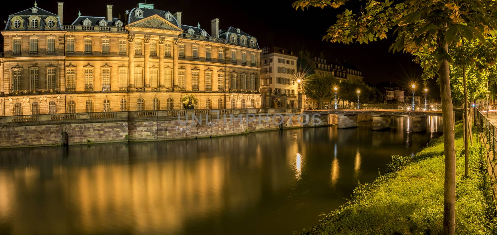 Night panoramic view with the Rohan Palace and the river Ill, with building and yellow lights reflected in its water.