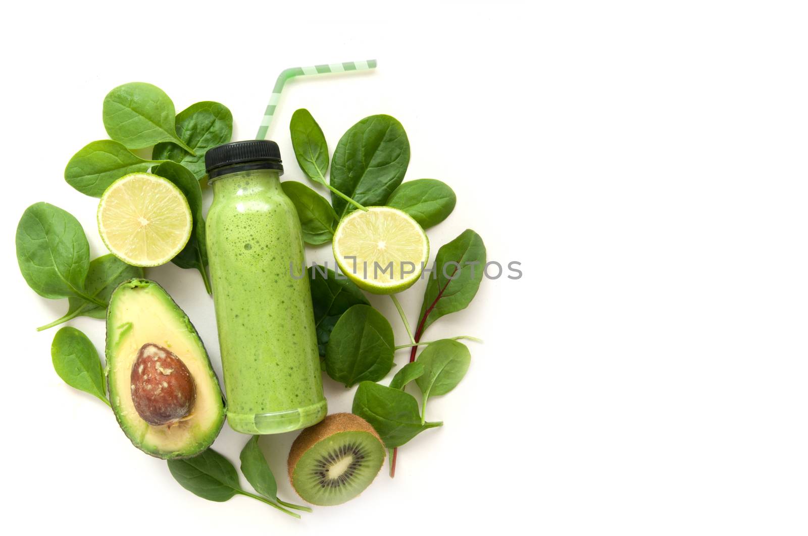 Bottled detox drink surrounded by green foods including spinach and kiwi 