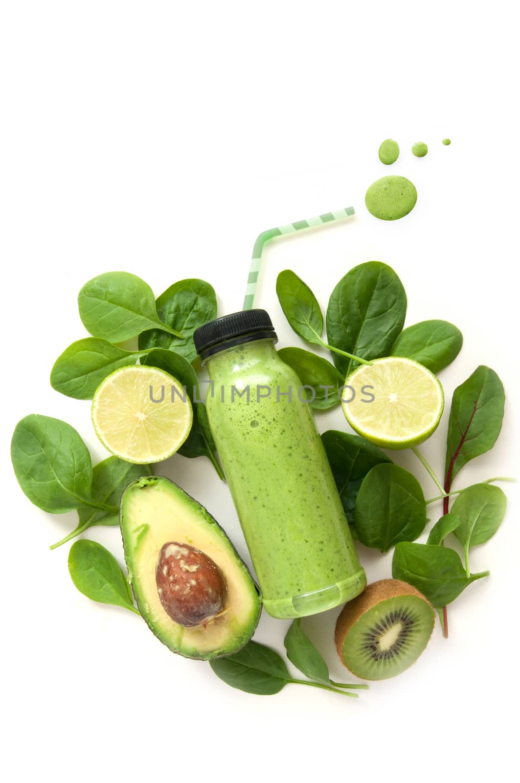 Bottled detox drink surrounded by green food ingredients with juice drops spilling out of a straw  