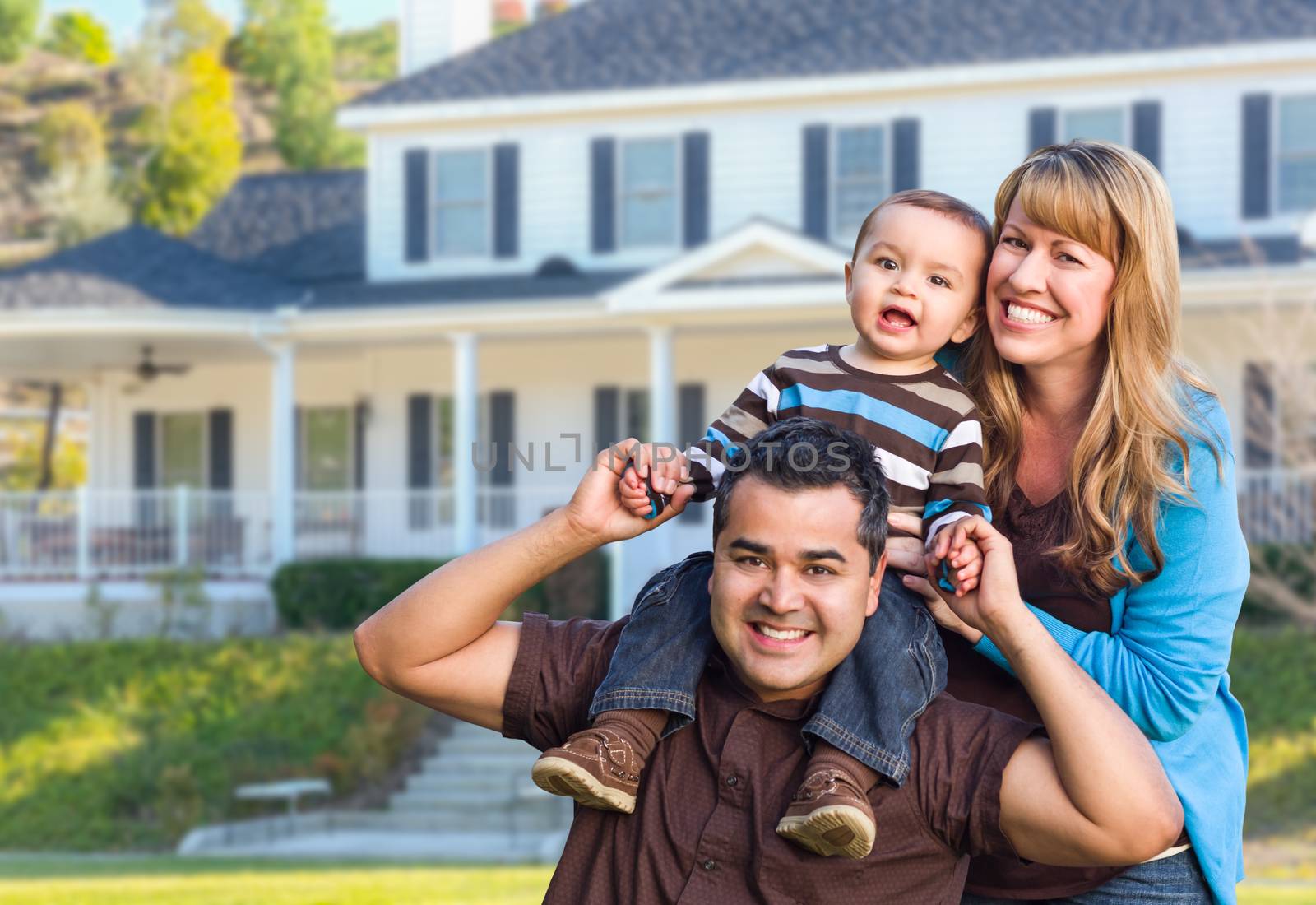 Happy Mixed Race Young Family in Front Yard of Beautiful House.
