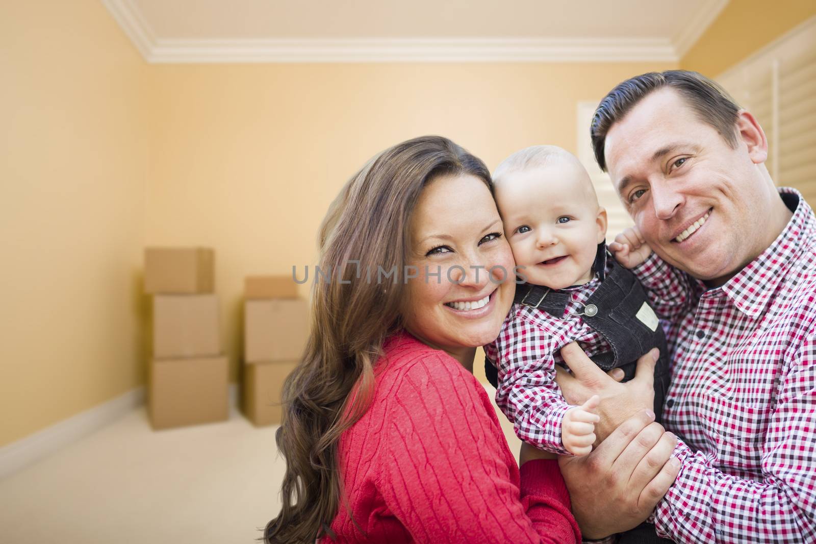 Happy Young Family In Room With Moving Boxes.