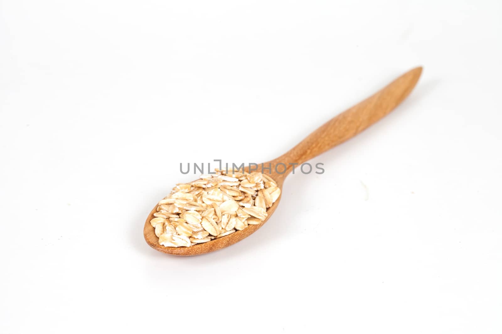 Oats flakes pile in wood spoon on white background