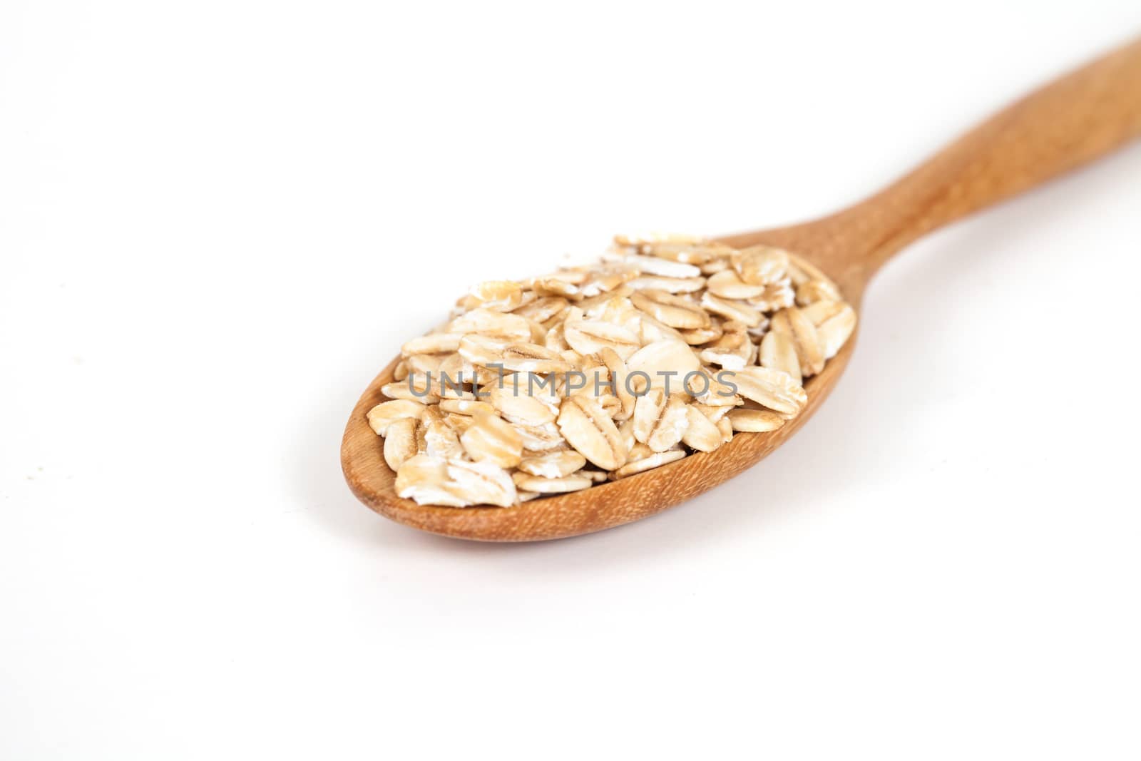 Oats flakes pile in wood spoon on white background