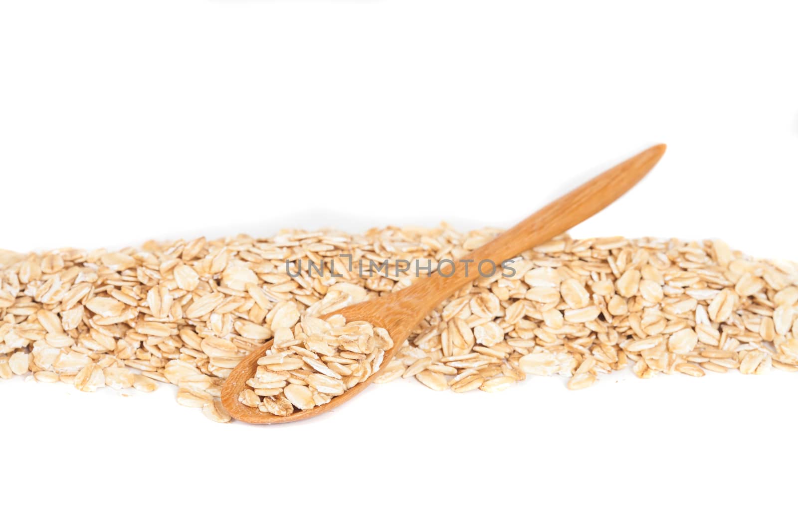 Oats flakes pile in wood spoon on white background