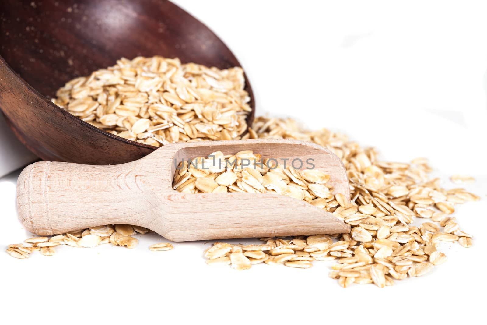 Oats flakes pile in wood spoon on white background