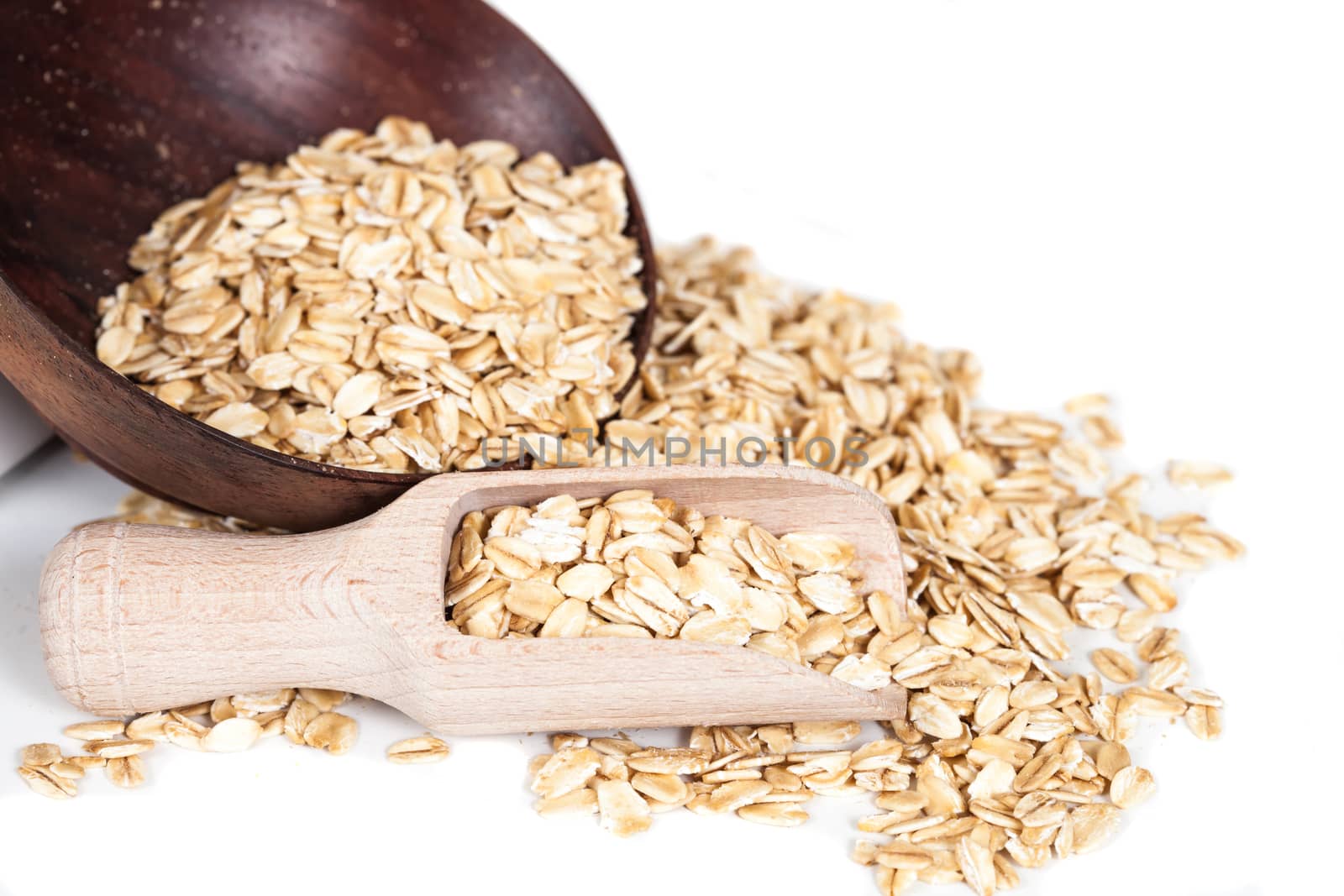 Oats flakes pile in wood spoon on white background