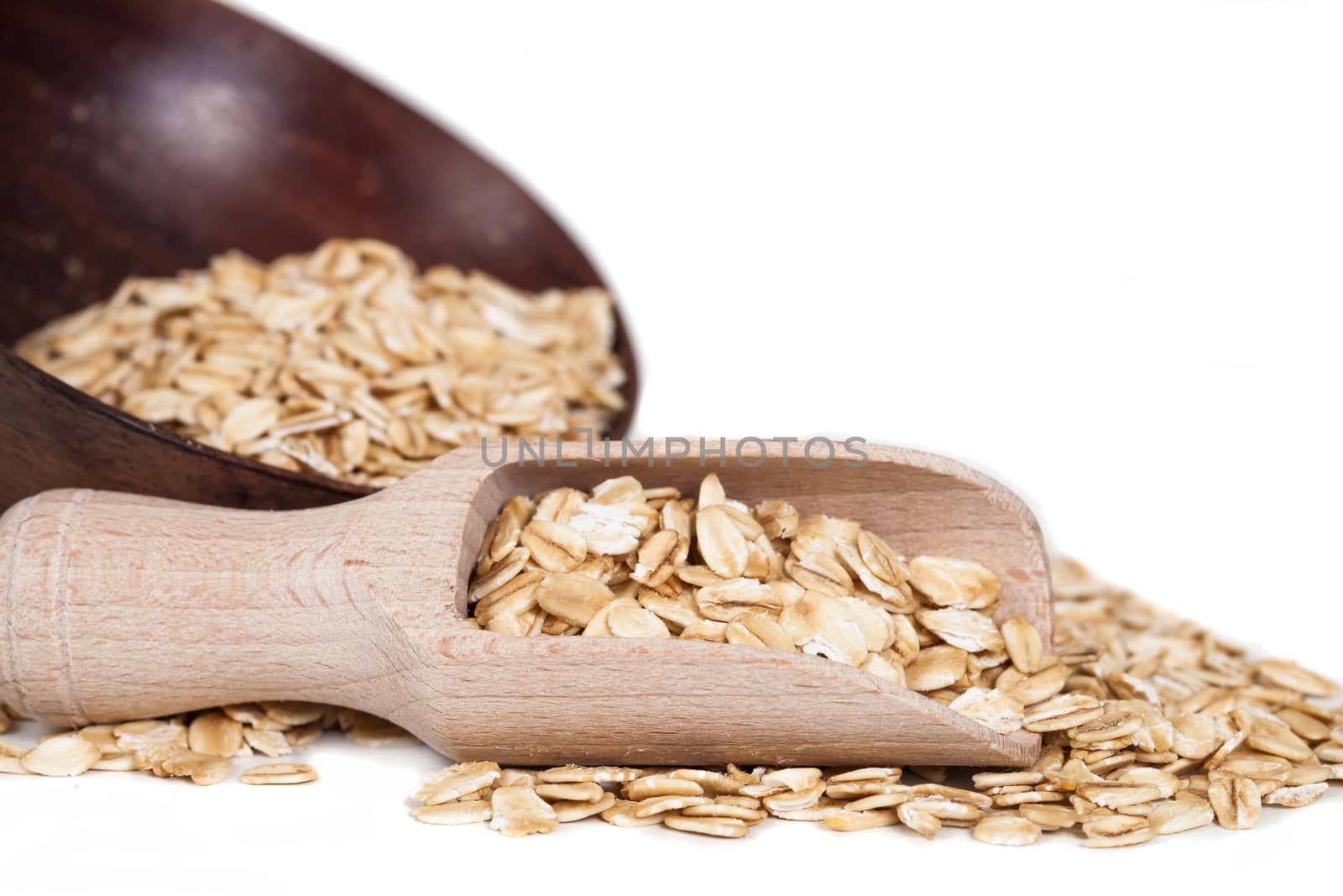 Oats flakes pile in wood spoon on white background