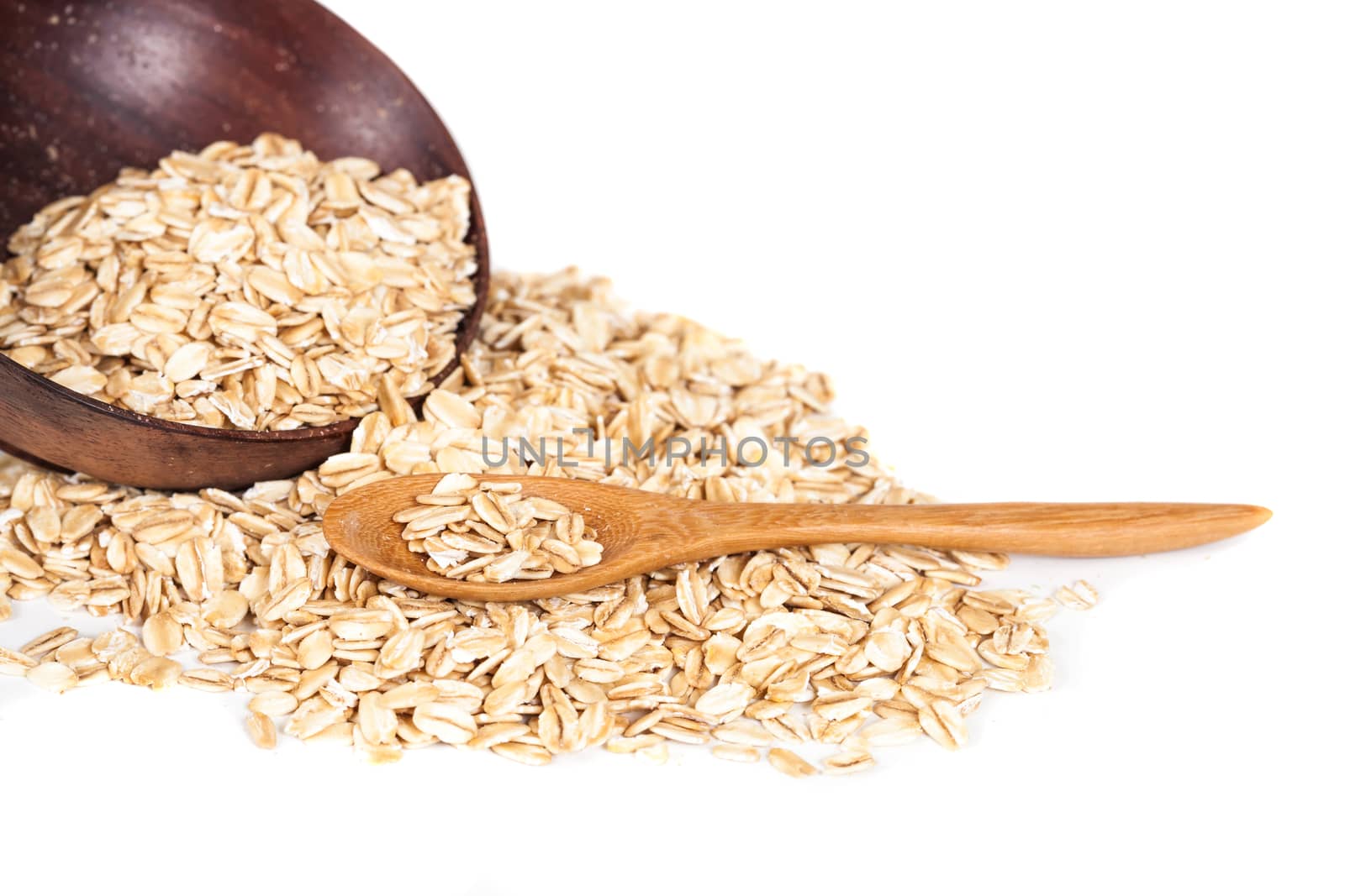 Oats flakes pile in wood spoon on white background